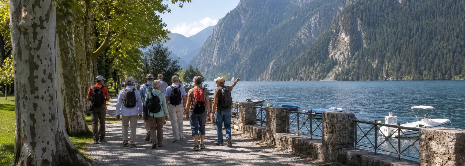 A guided walking group on the lakeside promenade under plane trees, the guide pointing out over the water
