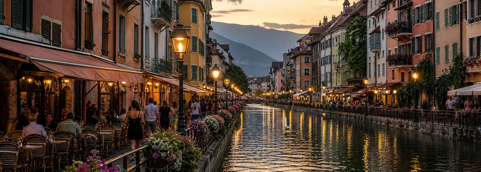 Café tables along a canal between pastel houses with green shutters in the evening light