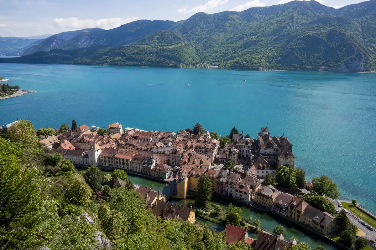 The Old Town seen from above: a compact block of terracotta roofs threaded by canals, dwarfed by the lake and the mountains behind it
